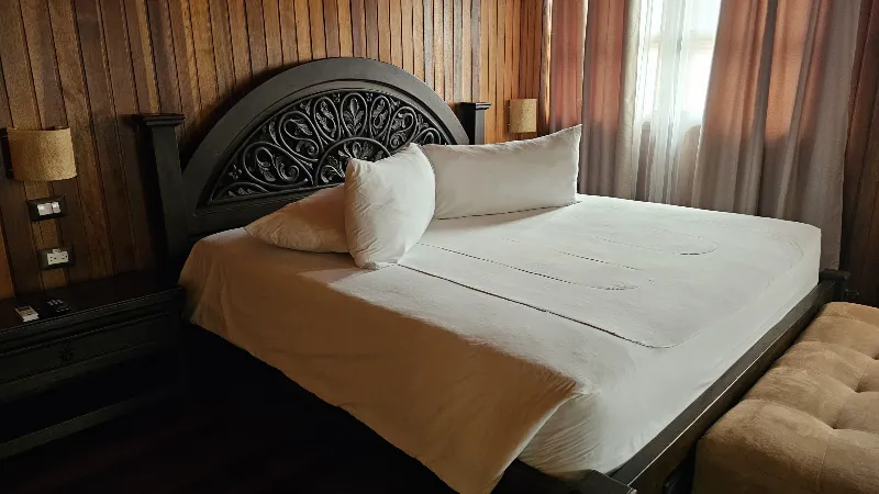 Sala luminosa con sofá esquinero beige, mesa de centro metálica y amplias ventanas con vista al jardín y montañas