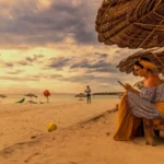 Mujer descansando bajo sombrilla de palma al atardecer en la playa de la isla de Cubagua, Nueva Esparta, Venezuela, cerca del glamping Cubagua Lodge