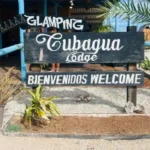 Letrero de bienvenida del glamping Cubagua Lodge con la inscripción "Bienvenidos Welcome" rodeado de plantas tropicales a la entrada del resort, isla de Cubagua, Nueva Esparta, Venezuela