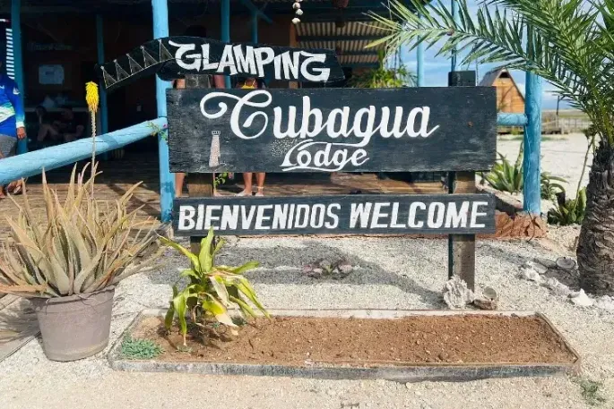 Letrero de bienvenida del glamping Cubagua Lodge con la inscripción "Bienvenidos Welcome" rodeado de plantas tropicales a la entrada del resort, isla de Cubagua, Nueva Esparta, Venezuela
