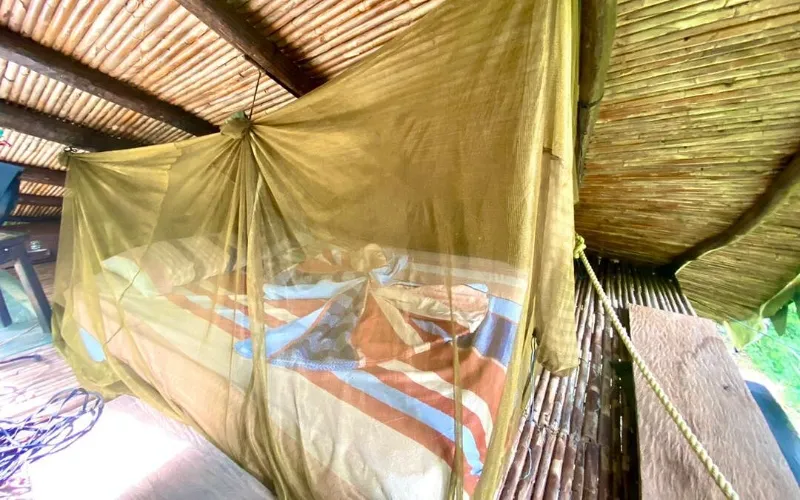 Interior de cabaña de la posada La Fuente con cama bajo mosquitero y techo de bambú en Caruao, La Guaira, Vargas, Venezuela
