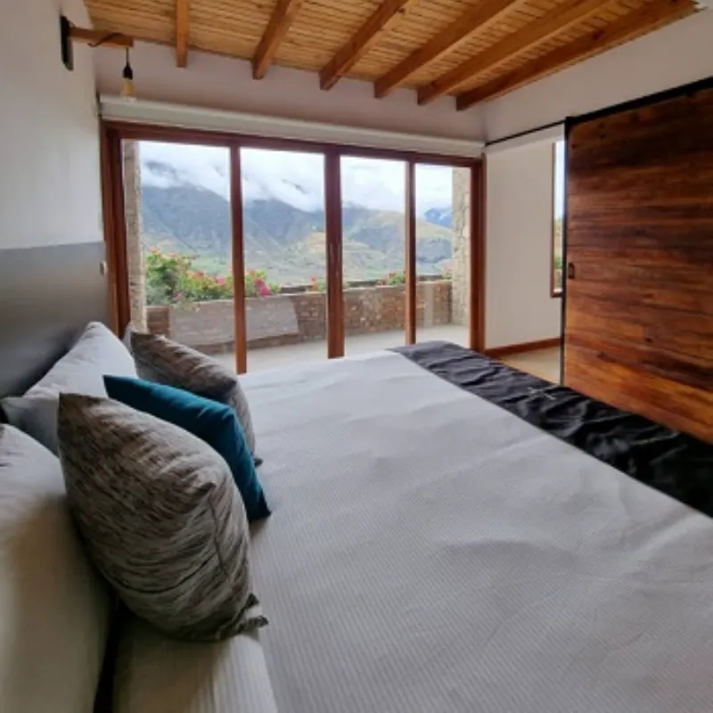 Habitación de cabaña de la posada Rafaela y Cristóbal con cama doble, techo de madera y puertas corredizas con vista a las montañas de Mucuchíes, Estado Mérida, Venezuela