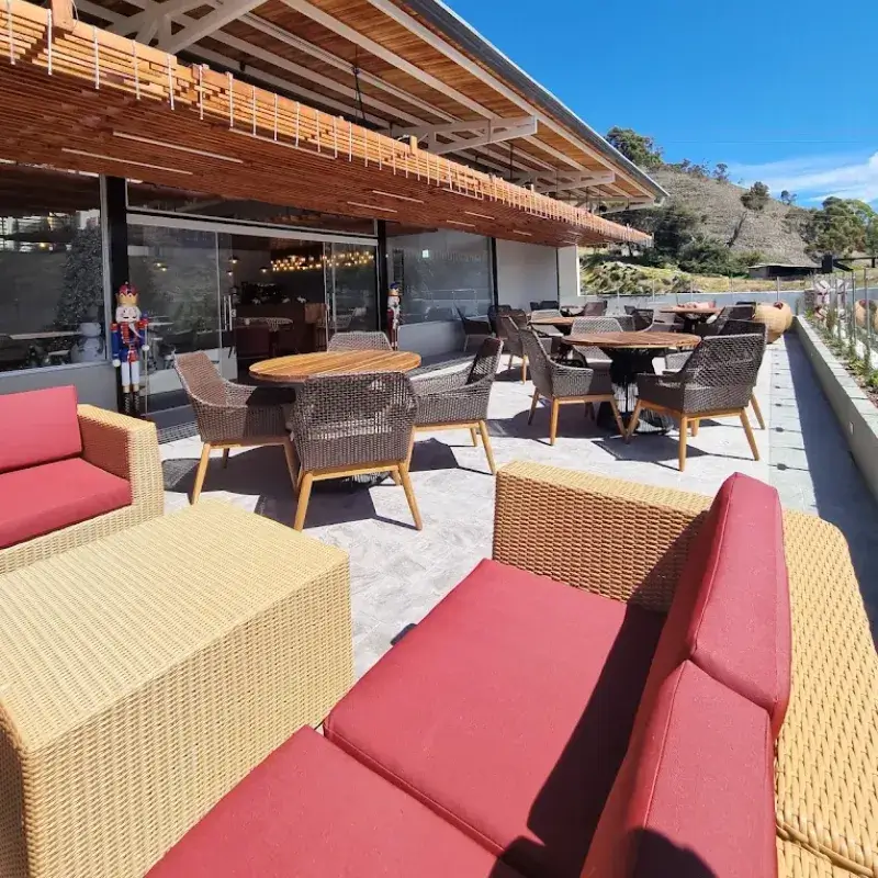 Terraza del restaurante de la posada Rafaela y Cristóbal con sofás rojos, mesas de madera y vista a las montañas andinas de Mucuchíes, Estado Mérida, Venezuela