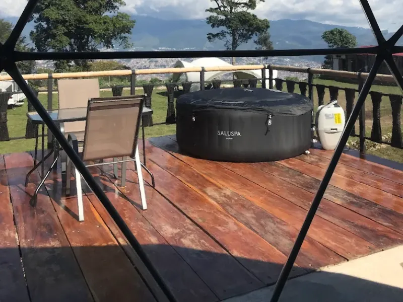 Deck de madera con jacuzzi portátil SaluSpa, sillas y vista panorámica al valle y montañas desde el domo