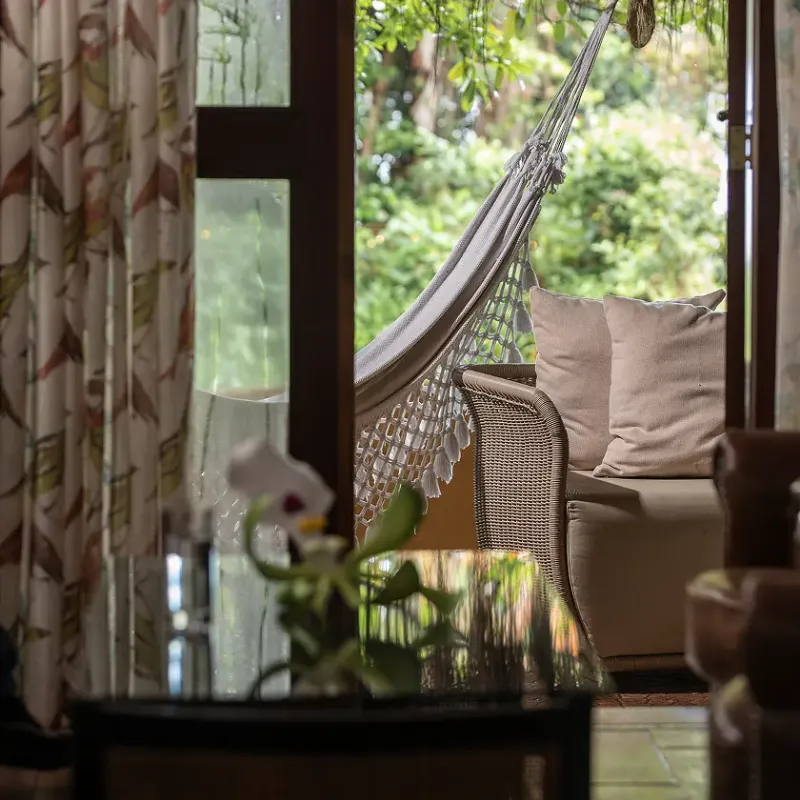 Terraza privada de cabaña del Waku Lodge con hamaca, sillón de mimbre y vista a la selva de Canaima, Venezuela