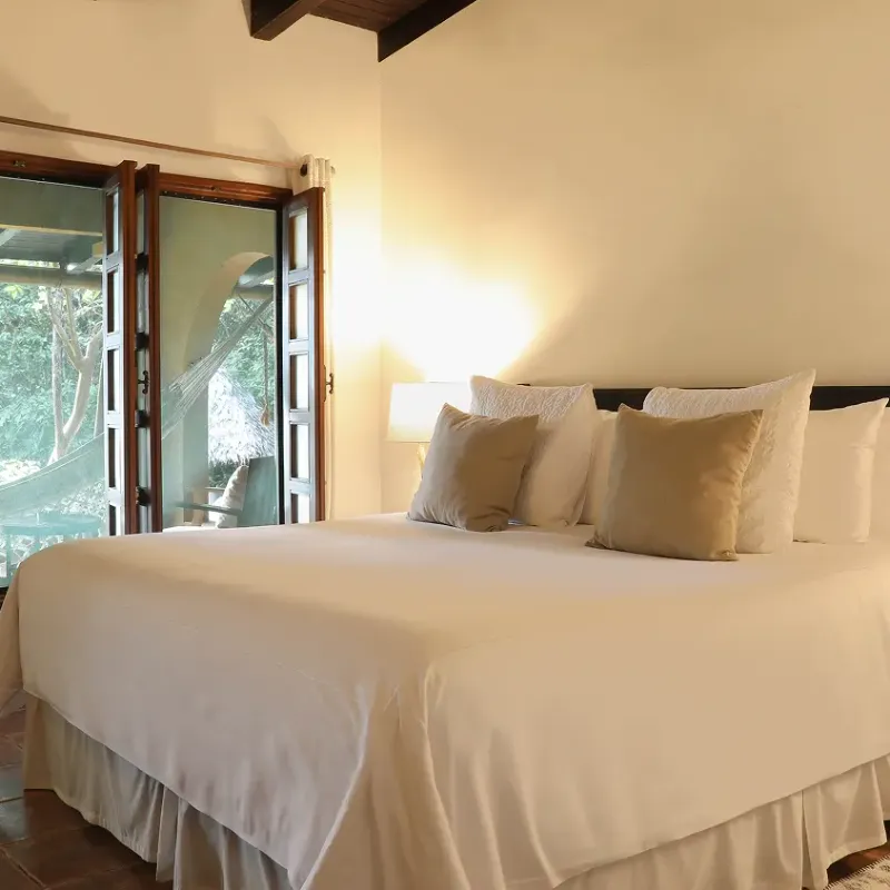 Habitación twin con dos camas, techo de madera y decoración cálida en el Waku Lodge, Canaima, Venezuela
